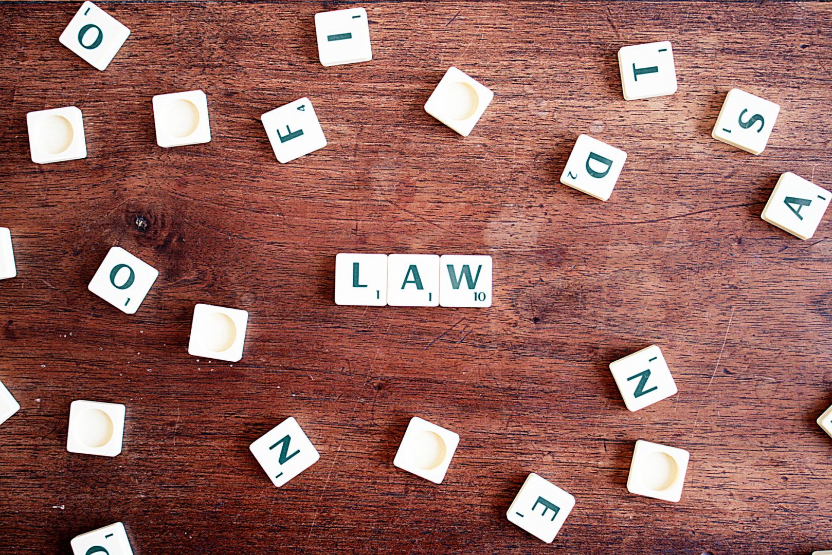 Obraz przedstawia napis law w języku angielskim, który ułożony jest z białych klocków z zielonymi literkami