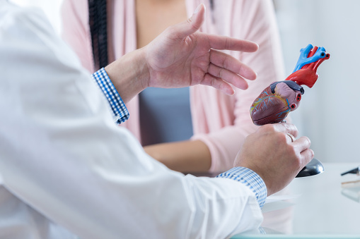 Mężczyzna kardiolog gestykuluje podczas omawiania diagnozy z nierozpoznaną pacjentką.